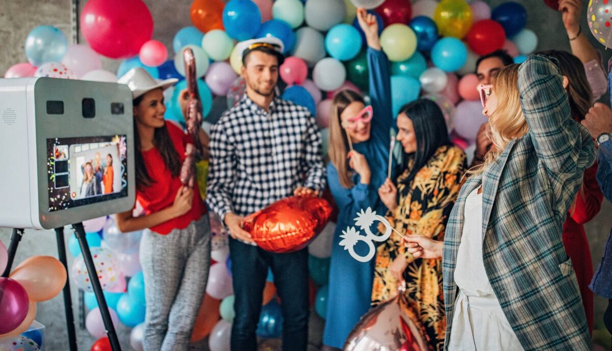 Invités qui prennent la pose devant un photobooth et un mur de ballons